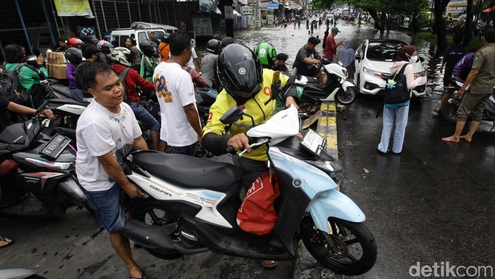 Banjir di Ciledug Mulai Surut, Jalanan Kusut Sejumlah pengendara menggotong kendaraan roda dua melintasi median jalan untuk menghindari banjir yang merendam jalan Raden Fatah, Ciledug, Kota Tangerang, Banten, Selasa (4/2/2025).