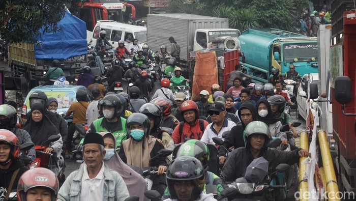 Banjir di Ciledug Mulai Surut, Jalanan Kusut Sejumlah pengendara menggotong kendaraan roda dua melintasi median jalan untuk menghindari banjir yang merendam jalan Raden Fatah, Ciledug, Kota Tangerang, Banten, Selasa (4/2/2025).