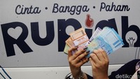 Warga menunjukkan uang rupiah baru hasil penukaran di mobil kas keliling BI.  