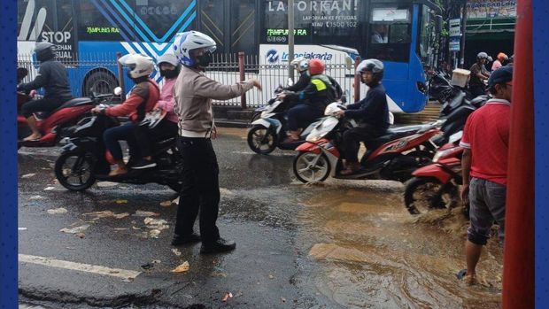 Genangan air di sekitar lampu merah Hek, Jakarta Timur menyebabkan kemacetan