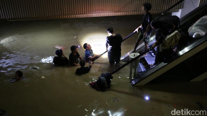 Pedagang menyelamatkan barang dagangan saat terjadi banjir di Mega Mall, Bekasi, Jawa Barat, Selasa (4/3/2025).