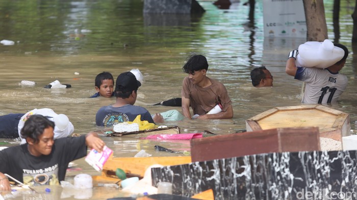 Pedagang menyelamatkan barang dagangan saat terjadi banjir di Mega Mall, Bekasi, Jawa Barat, Selasa (4/3/2025).