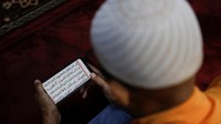 Warga menunggu waktu berbuka puasa dengan membaca Al-Quran. 
