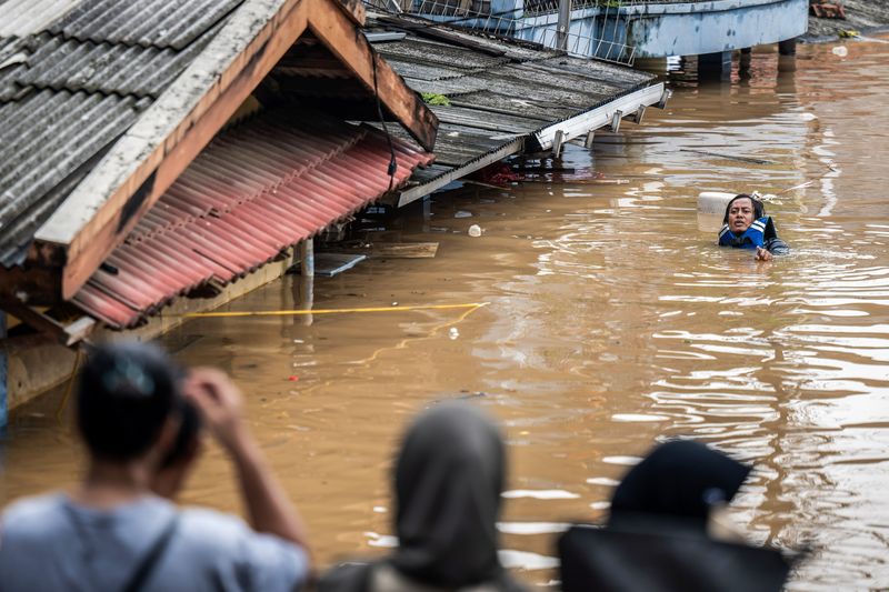 Warga melintasi banjir di Kelurahan Rawajati, Pancoran, Jakarta Selatan, Selasa (4/3/2025). Berdasarkan data BPBD DKI Jakarta pada Selasa (4/3) sebanyak 59 RT dan empat ruas jalan terdampak banjir dengan ketinggian 30 - 300 cm akibat luapan sungai Ciliwung. ANTARA FOTO/Bayu Pratama S/agrc