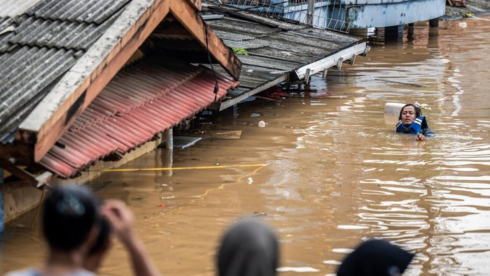 Warga melintasi banjir di Kelurahan Rawajati, Pancoran, Jakarta Selatan, Selasa (4/3/2025). Berdasarkan data BPBD DKI Jakarta pada Selasa (4/3) sebanyak 59 RT dan empat ruas jalan terdampak banjir dengan ketinggian 30 - 300 cm akibat luapan sungai Ciliwung. ANTARA FOTO/Bayu Pratama S/agrc