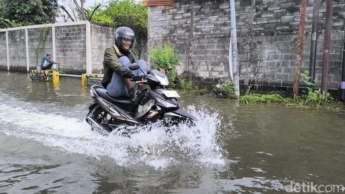 Pengendara roda dua menerobos banjir di Jalan Boboh, Menganti Gresik