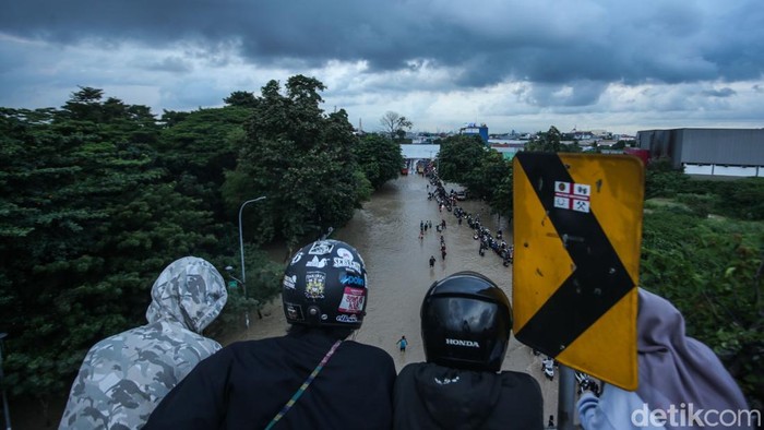 Ojek online membonceng penumpang melewati banjir di Bekasi, Selasa (4/3/2025).