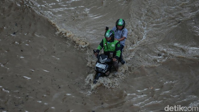 Perjuangan Pulang ke Rumah Lewati Banjir Bekasi Ojek online membonceng penumpang melewati banjir di Bekasi, Selasa (4/3/2025).