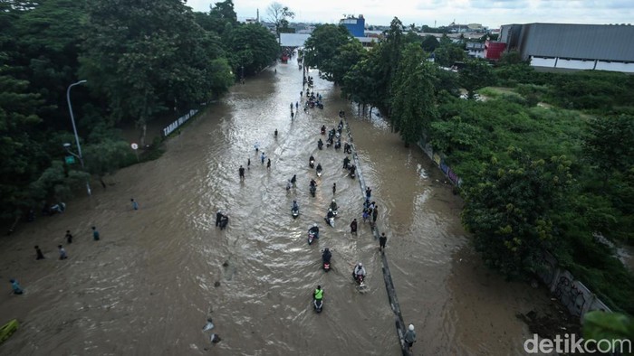Ojek online membonceng penumpang melewati banjir di Bekasi, Selasa (4/3/2025).