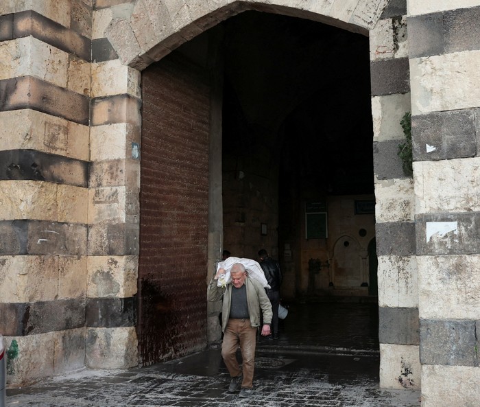 A man walks as he carries a bag, during the Muslim holy fasting month of Ramadan in Aleppo, Syria, March 2, 2025. REUTERS/Mahmoud Hassano