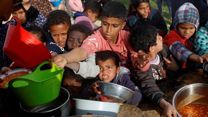 Teriakan Anak-anak Gaza Berebut Makanan untuk Buka Puasa Palestinian children gather to receive food cooked by a charity kitchen, during the Muslim holy month of Ramadan, in Khan Younis, in the southern Gaza Strip, March 3, 2025. REUTERS/Hatem Khaled TPX IMAGES OF THE DAY