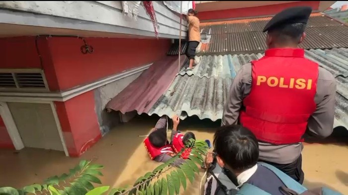 Warga di Bekasi yang terjebak banjir terpaksa harus naik genteng saat dievakuasi polisi. (Dok istimewa).