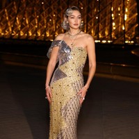 Gaun panjang dengan ekor menyentuh lantai ini terbuat dari tiga potong pakaian yang disatukan. Untuk melengkapi penampilannya, kekasih aktor Bradley Cooper ini memakai perhiasan emas dan perak. Foto: Stephane Cardinale - Corbis/Corbis via Getty Images