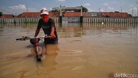 Warga melintas di jalanan yang terendam banjir di Kampung Gabus Rawa, Desa Srijaya, Tambun Utara, Kabupaten Bekasi, Jawa Barat.