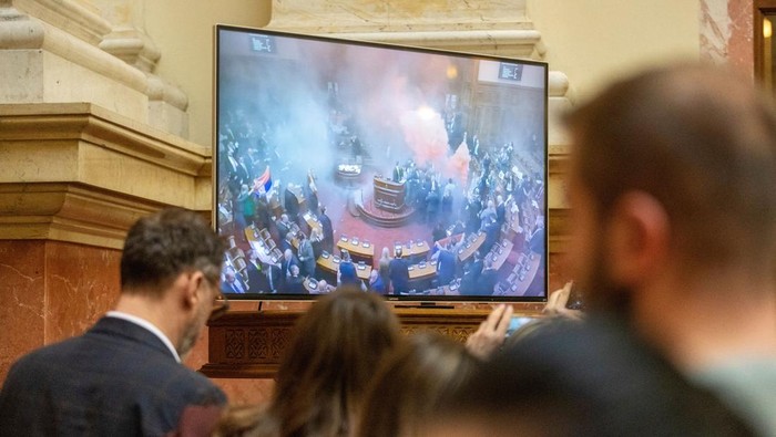 Journalists watch live broadcast while opposition members of parliament let off smoke grenade inside Serbian parliament, in Belgrade, Serbia, March 4, 2025. REUTERS/Djordje Kojadinovic