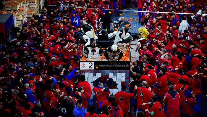 Potret Keseruan Tradisi Perang Jeruk di Italia Revellers take part in a fight with oranges during an annual carnival battle in Ivrea, Italy, March 2, 2025. REUTERS/Massimo Pinca
