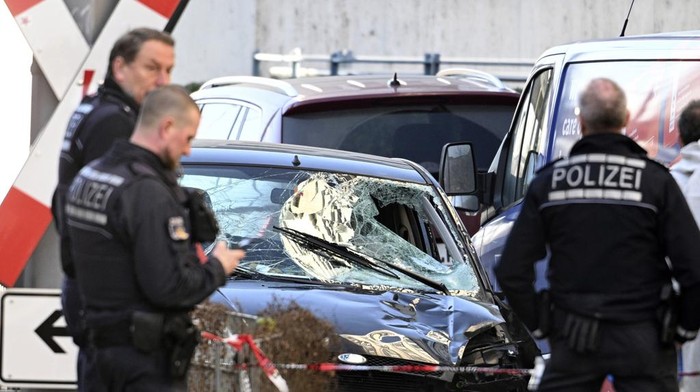 Police officers stand next to a damaged vehicle in the city center of Mannheim, Germany, Monday March 3, 2025, following an incident in which one person was killed and others injured when a car rammed into a crowd, German police said. (Boris Roessler/dpa via AP)