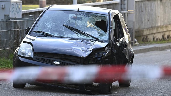 Police officers stand next to a damaged vehicle in the city center of Mannheim, Germany, Monday March 3, 2025, following an incident in which one person was killed and others injured when a car rammed into a crowd, German police said. (Boris Roessler/dpa via AP)
