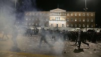 Sejumlah massa berlarian saat bentrokan dengan polisi di Luar Gedung Parlemen, Athena, Yunani, Rabu (5/3/2025).