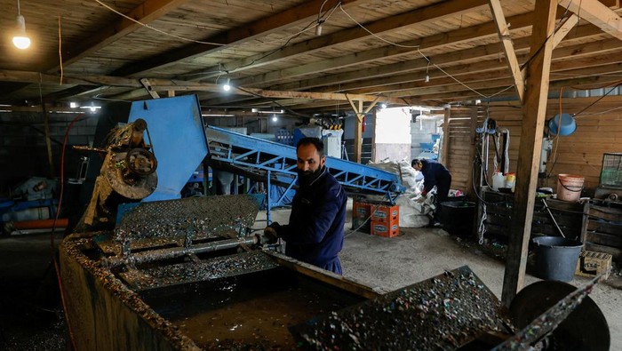 Workers process plastic items in machines donated by the U.S. government that shred and clean the plastic so it can be sold for reuse, in Fushe Kosove, Kosovo February 24, 2025. REUTERS/Valdrin Xhemaj