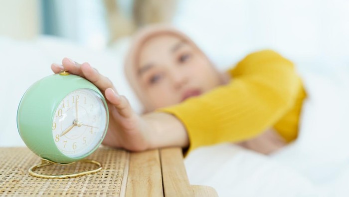 Beautiful Asian muslim young woman sleeping - relaxing on the bed during the day. Cozy and relaxing lifestyle of modern muslim woman concept.