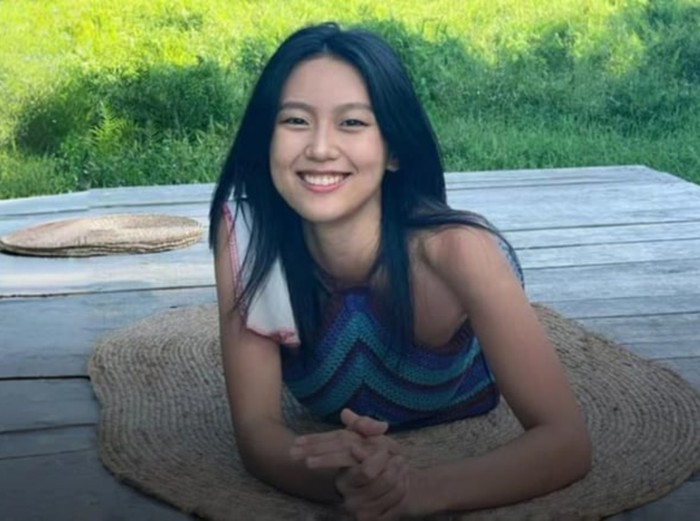 Young woman applying lipstick at a cafe