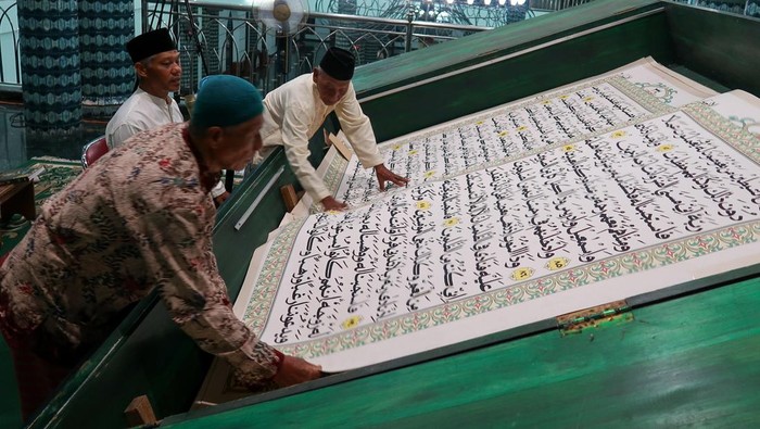 Warga tadarus menggunakan Al Quran raksasa di Masjid Agung Baiturrahman, Banyuwangi, Jawa Timur, Rabu (5/3/2025). Tradisi tadarus Al Quran raksasa berukuran 142 x 210 centimeter yang ditulis tangan oleh Abdul Karim pada tahun 2010 itu membutuhkan dua orang petugas untuk membalikkan setiap lembar Al Quran ketika mencapai halaman berikutnya. ANTARA FOTO/Budi Candra Setya/agr