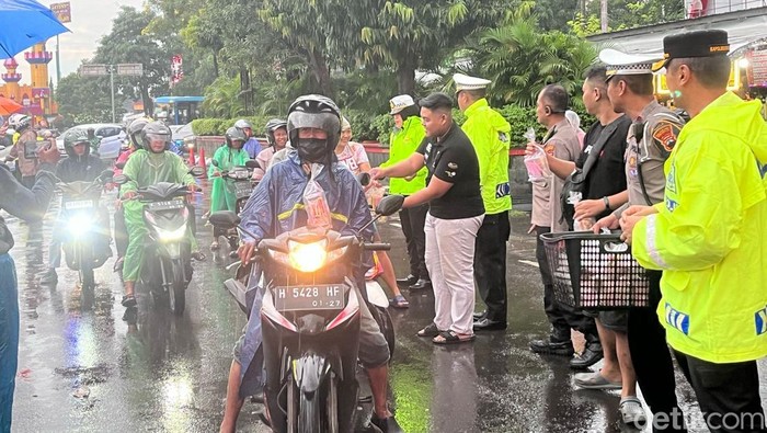 Polisi bagi-bagi takjil ke pengguna jalan saat hujan di Simpang Lima, Semarang, Jumat (7/3/2025).