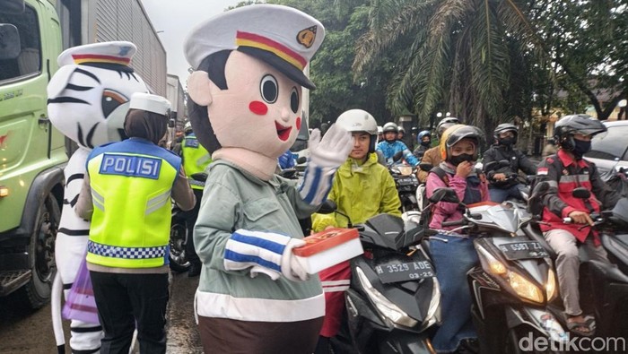 Polisi membagikan takjil di traffic light lingkar depan SMPN I Demak, Jumat (7/3/2025).