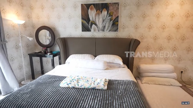 Kamar utama bernuansa putih dengan sentuhan abu-abu pada laci, gorden, dan lukisan bunga. Terlihat banyak ruang penyimpanan seperti rak, laci, dan lemari. (Foto: Tangkapan Layar YouTube TRANS7 OFFICIAL)