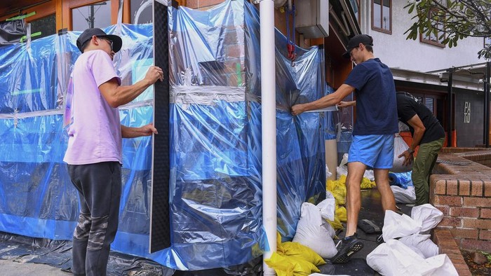 Owners work to protect their cafe with sandbags and plastic sheets in the Brisbane suburb of Rosalie, Australia, Friday, March 7, 2025. (Jono Searle/AAP Image via AP)