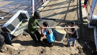 Para warga turut bergotong royong di titik longsor dengan jembatan yang konstruksi penopangnya amblas akibat tergerus arus banjir. (dok BNPB)