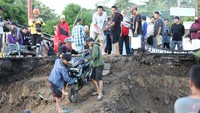 Hingga kini masih tampak beberapa warga yang menurunkan dan menaikkan kendaraan roda dua dengan tali tambang. (dok BNPB)