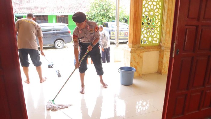 Polisi membantu membersihkan lumpur sisa banjir di masjid kawasan Babelan, Kabupaten Bekasi.
