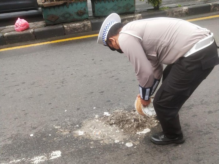 Polisi menutup jalan berlubang di Ciputat, Tangsel dengan puing-puing. Jalan berlubang ini bikin pemotor terjatuh.