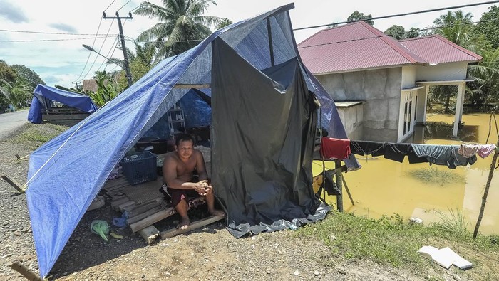 Warga duduk di dalam tenda darurat yang didirikan untuk tempat menginap sementara saat banjir merendam kawasan permukiman Desa Punti Kalo, Sumay, Tebo, Jambi, Sabtu (8/3/2025). Sejumlah warga yang terdampak banjir luapan Sungai Batanghari sejak Rabu (5/3/2025) memilih mendirikan tenda darurat di tempat yang lebih tinggi di dekat rumahnya sebagai tempat menginap sementara. ANTARA FOTO/Wahdi Septiawan/rwa.