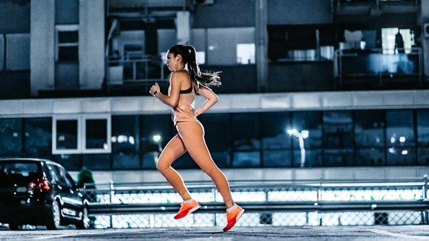 Young beautiful athlete Caucasian woman jogging in public garage at night.