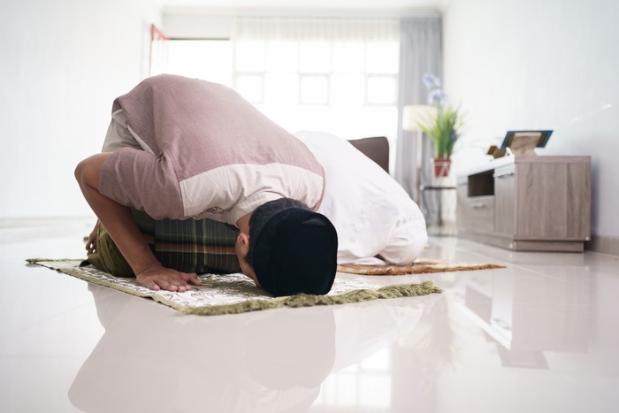 asian muslim husband and wife praying jamaah together at home. sujud