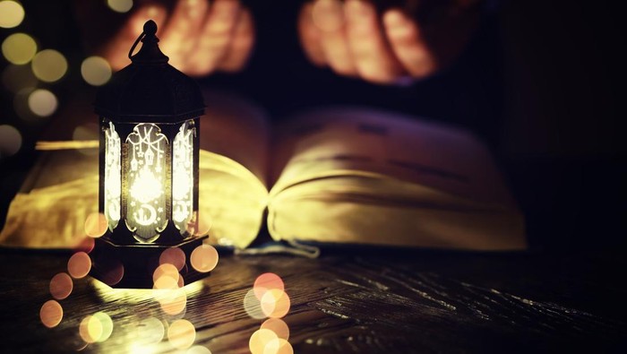 Ornamental Arabic lantern burning candle glowing at night. Festive greeting card, invitation for Muslim holy month Ramadan Kareem.