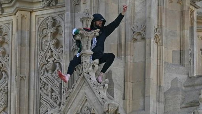 A protester holding a Palestinian flag gestures from the side of the Elizabeth Tower, commonly known by the name of the clocks bell 