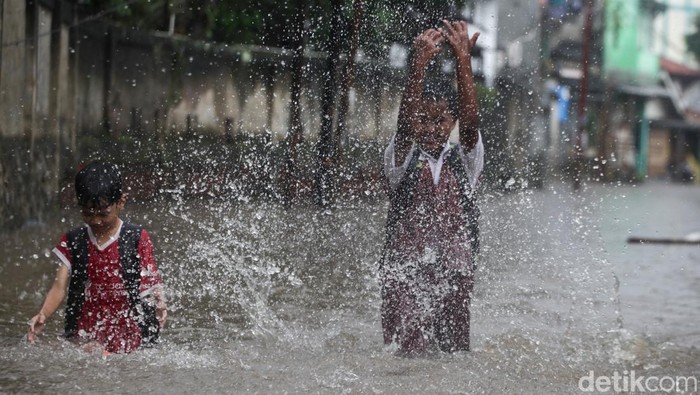 Anak-anak melewati banjir di Jl Kemuning III, Pamulang, Tangsel, Senin (10/3/2025). Jalanan banjir akibat hujan deras yang mengguyur.