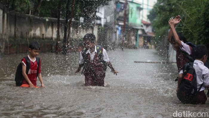 Diguyur Hujan Deras, Jalanan di Pamulang Tangsel Banjir Anak-anak melewati banjir di Jl Kemuning III, Pamulang, Tangsel, Senin (10/3/2025). Jalanan banjir akibat hujan deras yang mengguyur.