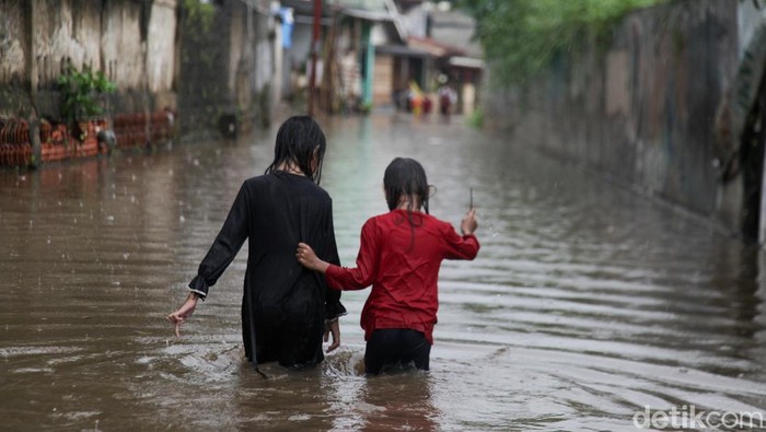 Diguyur Hujan Deras, Jalanan di Pamulang Tangsel Banjir Anak-anak melewati banjir di Jl Kemuning III, Pamulang, Tangsel, Senin (10/3/2025). Jalanan banjir akibat hujan deras yang mengguyur.