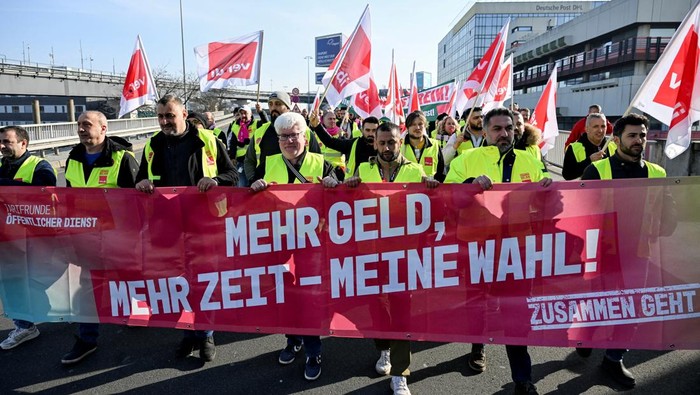 Pekerja Bandara di Jerman Mogok Kerja, Protes soal Upah Workers hold a banner as they demonstrate during a 24-hour strike at the Frankfurt Airport called by the German trade union Verdi over a wage dispute in Frankfurt, Germany March 10, 2025. The banner reads,