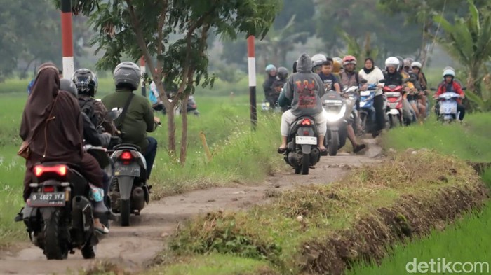 Pemotor lewati pematang sawah karena banjir di kawasan Sapan, Bojongsoang, Kabupaten Bandung, Senin 10 Maret 2025