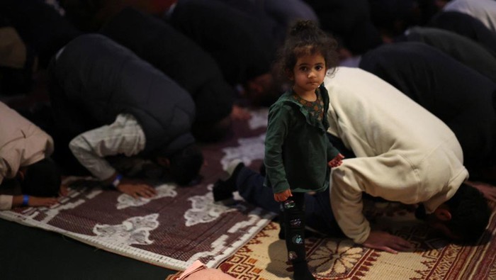 Potret Umat Muslim London Buka Puasa Bersama A child looks on as people pray during Open Iftar 2025 organised by the Ramadan Tent Project at Shakespeare's Globe in London, Britain, March 9, 2025. REUTERS/Hannah McKay