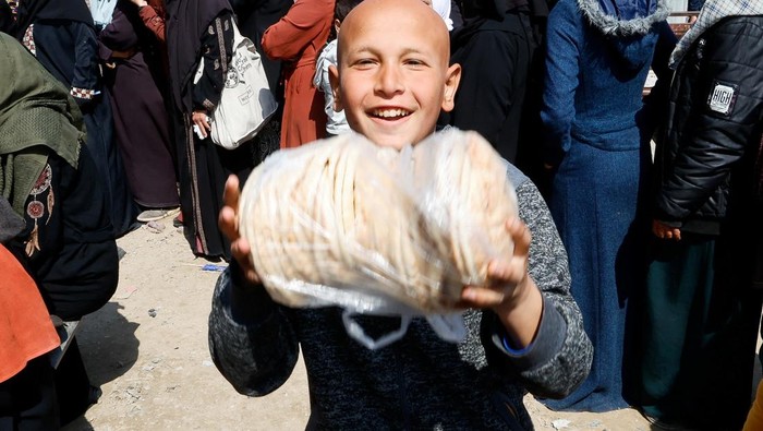 A Palestinian child reacts as he and others gather to receive bread from a bakery, in Khan Younis, in the southern Gaza Strip, March 9, 2025. REUTERS/Hatem Khaled