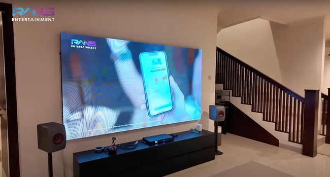 Tak dipenuhi dengan banyak barang, meja di bawah televisinya tampak rapih. Di bagian kiri dan kanan televisi miliknya Ariel juga menambahkan speaker. Foto: YouTube/Rans Entertainment