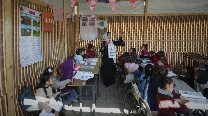 Palestinian children take a lesson in a makeshift classroom located within a school compound, which is also serving as a shelter for displaced people in Gaza City, Monday March 10, 2025. (AP Photo/(AP Photo/Jehad Alshrafi)