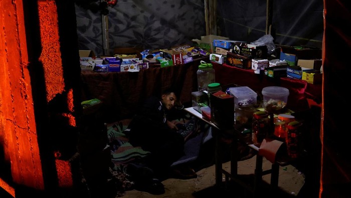 A Palestinian man rests in a makeshift shop during a power cut, in Rafah in the southern Gaza Strip, March 9, 2025. REUTERS/Hatem Khaled